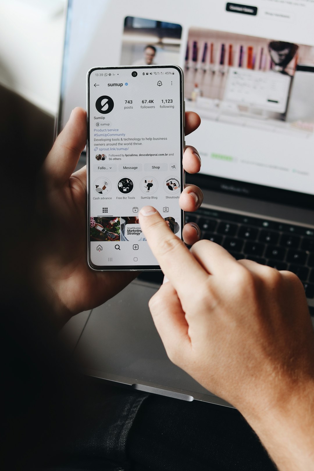 Une personne tient un smartphone et consulte le profil Instagram de SumUp.